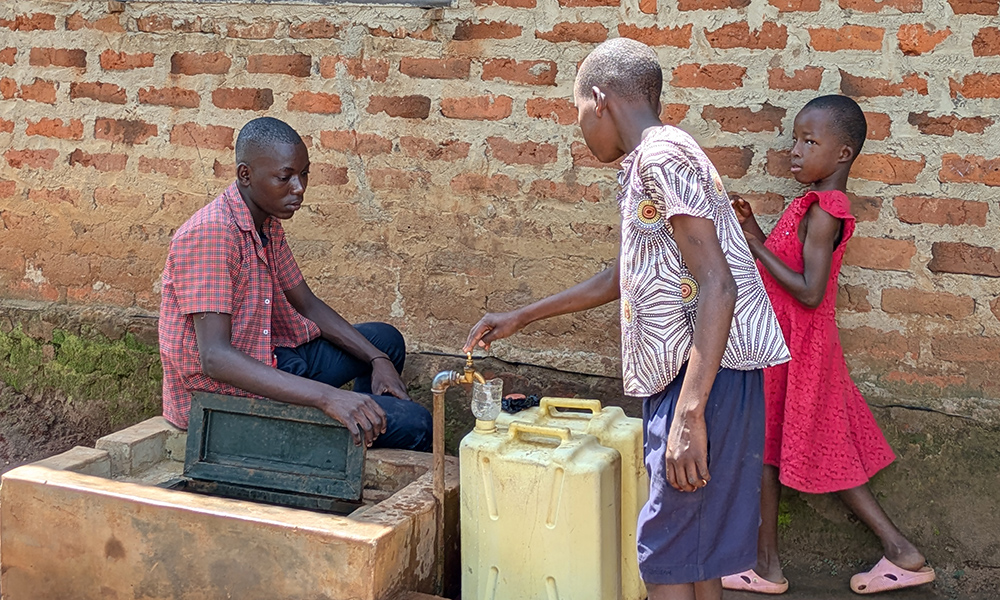 Barn hämtar vatten i en brunn.