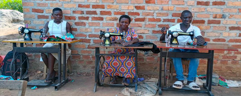 Tre personer vid varsin symaskin.