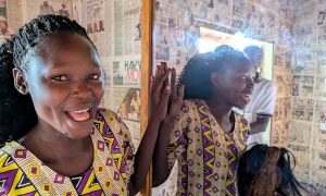 Glad kvinna i Uganda vid spegel i hårsalong.