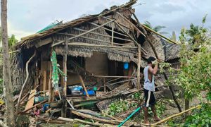 Man framför ödelagt hus.