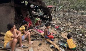 Familj med barn framför ödelagt hus.