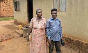 Kvinna och man framför enkelt hus i Uganda.